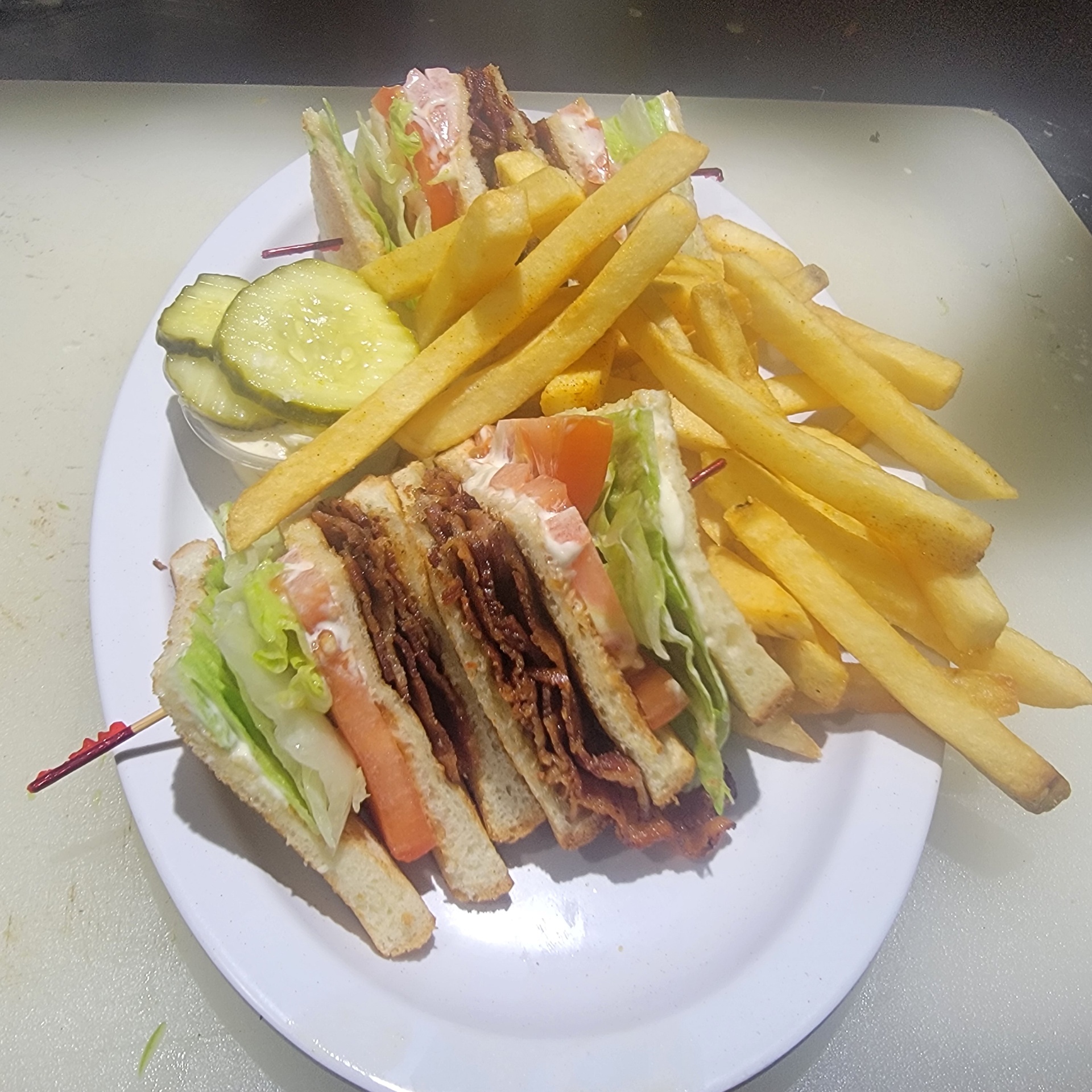 Bacon club sandwich with fries and pickle
