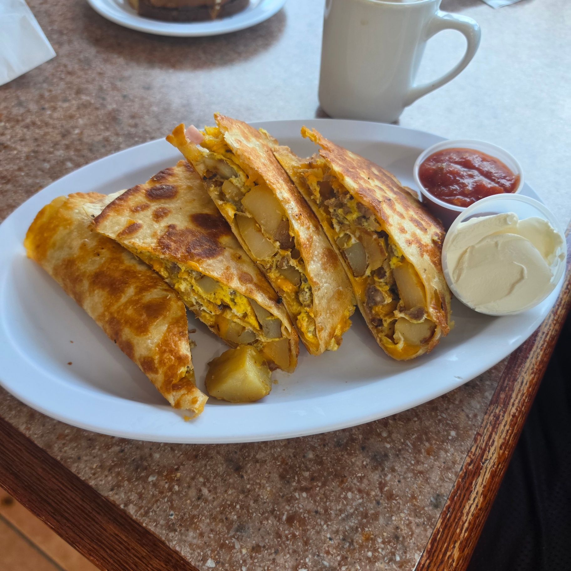 Sausage, egg and cheese breakfast quesadilla with salsa, sour cream and coffee
