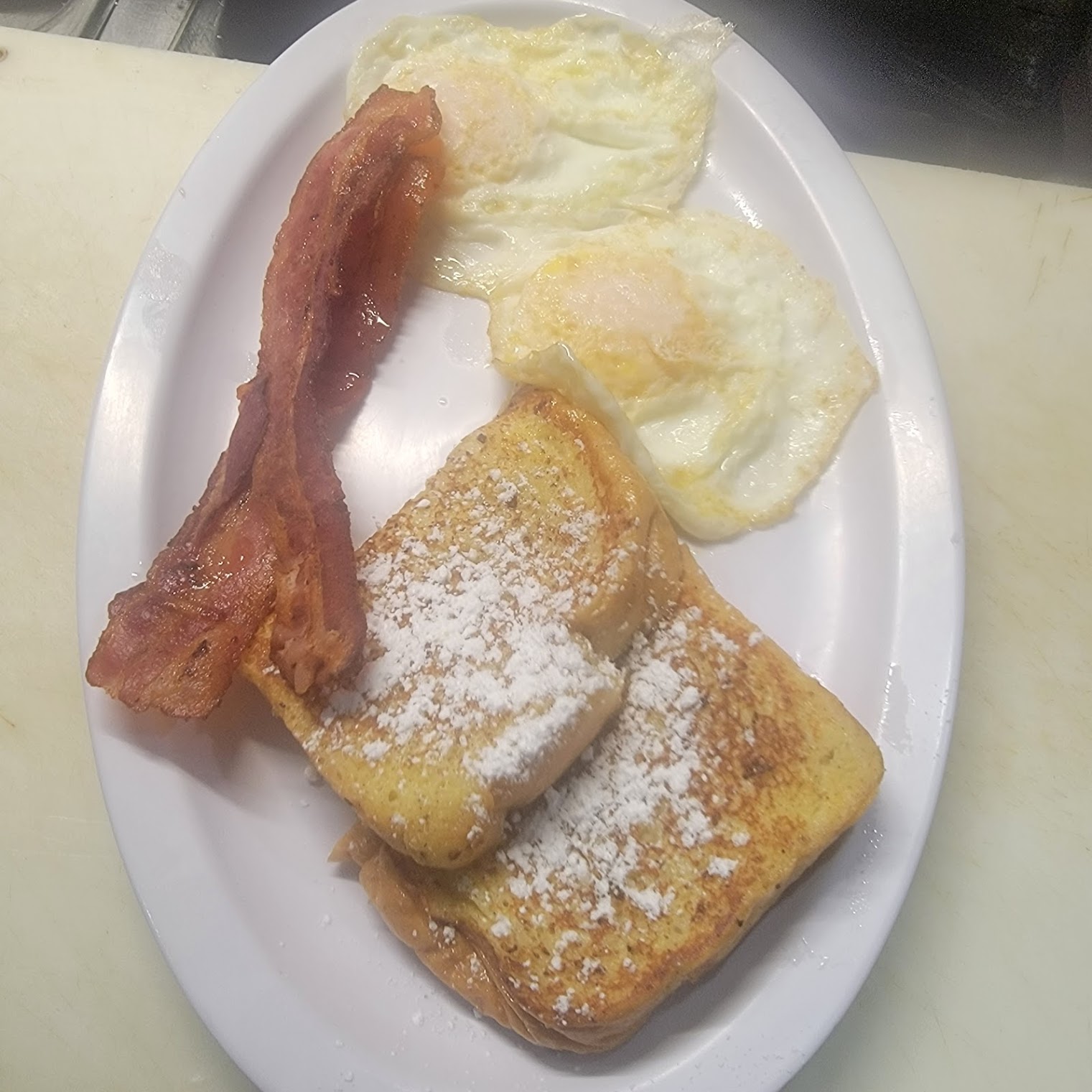 Classic Breakfast Combo at Toasted Cafe — Two eggs, crispy bacon, golden French toast and fluffy pancakes — everything you want in one plate.