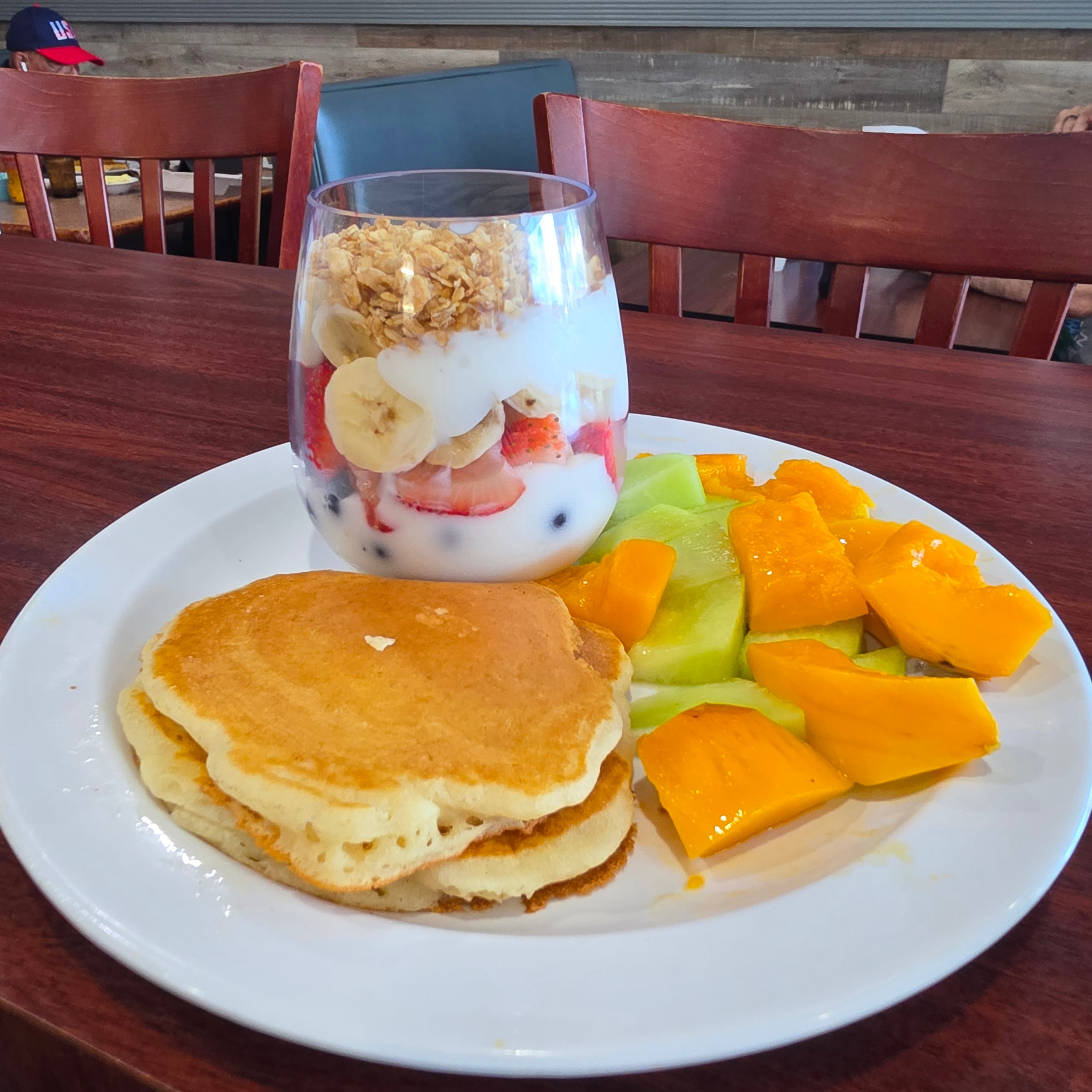 Yogurt parfait with granola and berries, pancakes and fresh mango