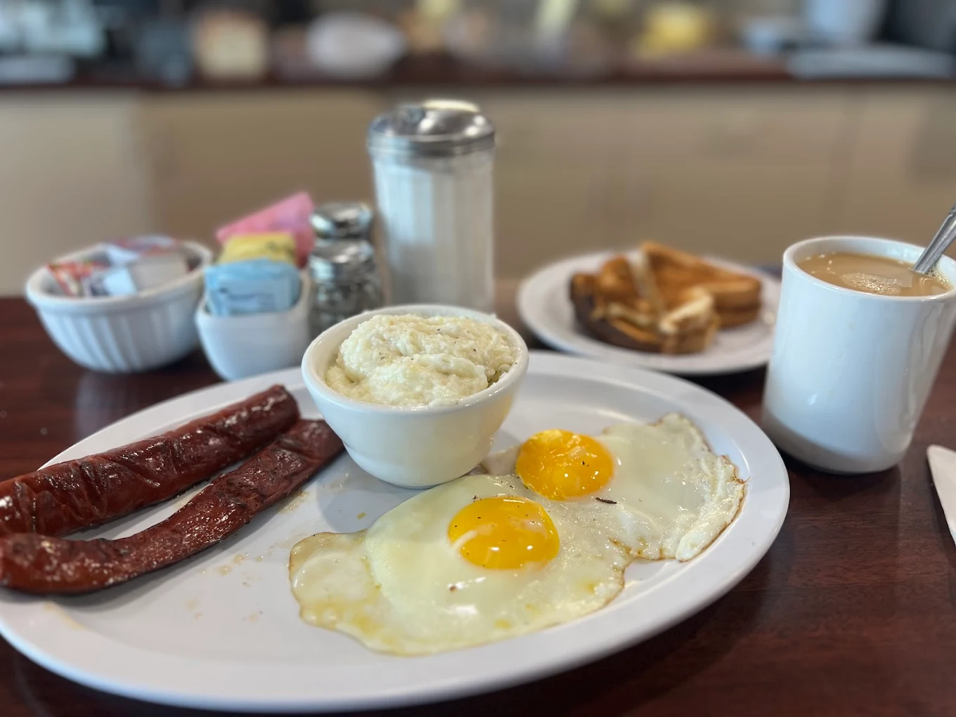 Eggs, sausage, grits and toast served with a cup of coffee