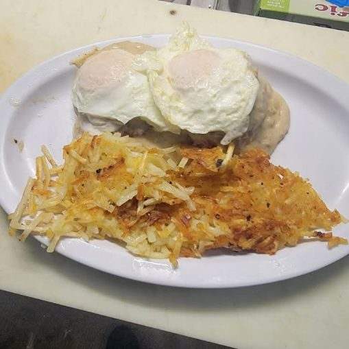 Country Breakfast at Toasted Cafe — Flaky biscuits under rich country gravy, topped with eggs and served with crispy hash browns.