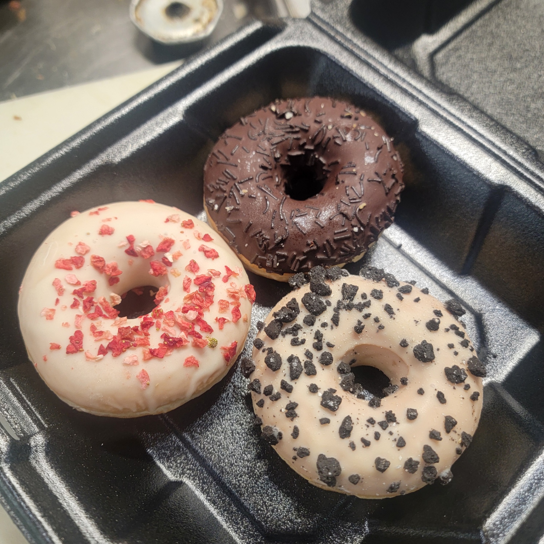 Trio of fresh donuts — strawberry, cookies and cream, and chocolate sprinkle