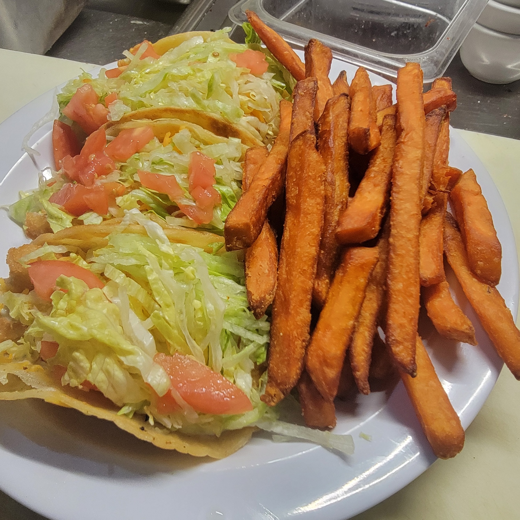 Crispy tacos with lettuce and tomato served with sweet potato fries