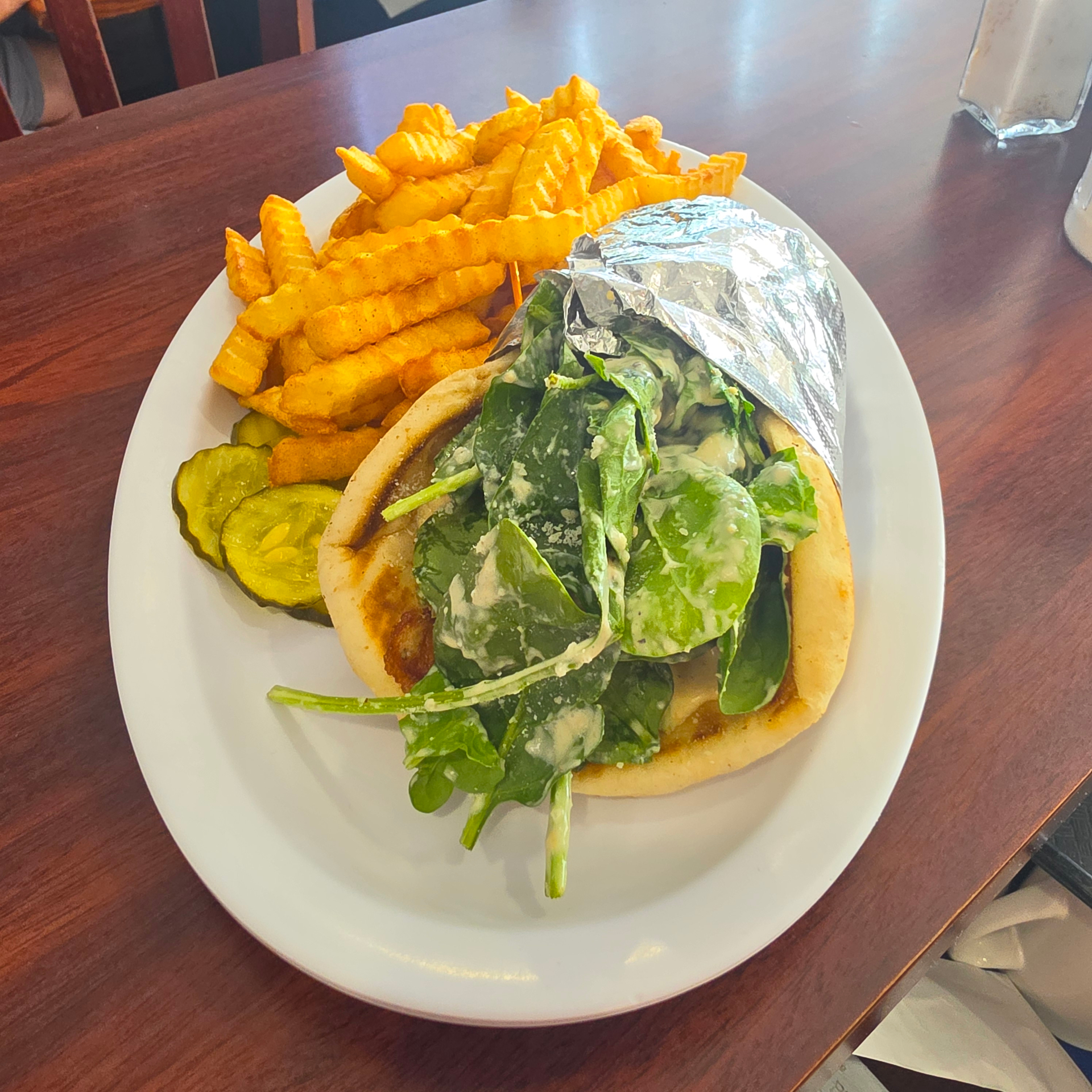 Spinach and feta gyro pita with crinkle-cut fries and pickles